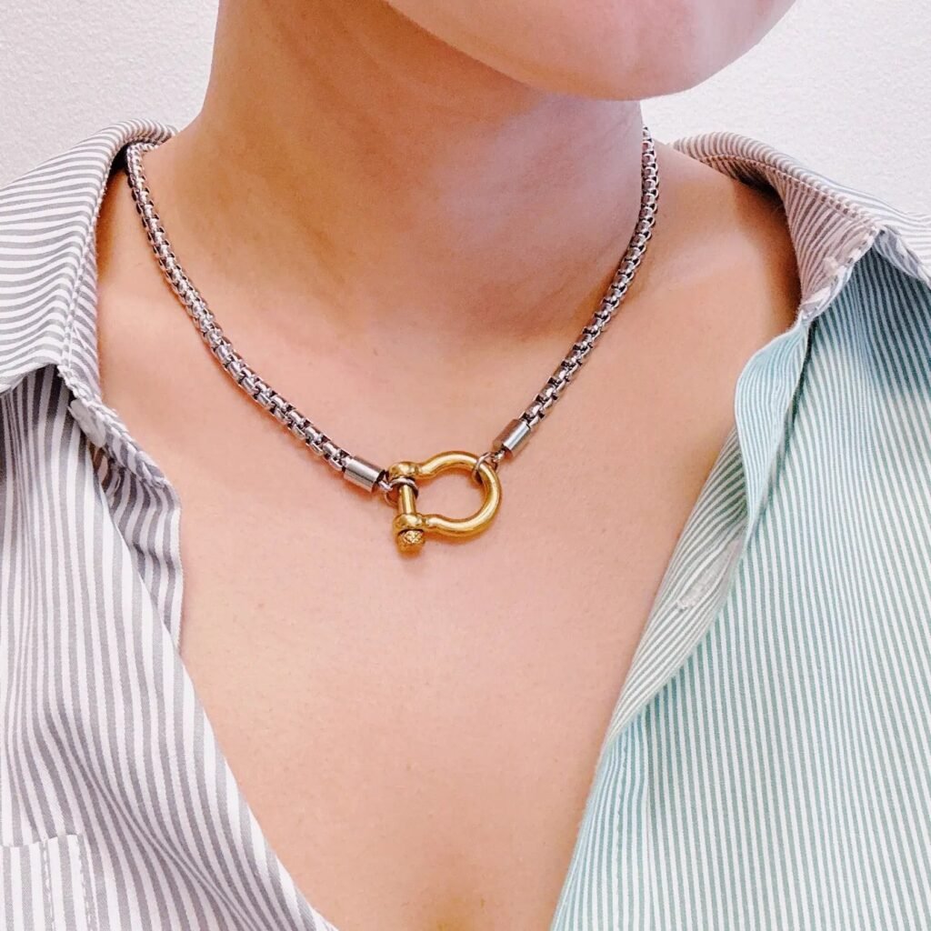 Woman wearing a box chain necklace with gold shackle pendant